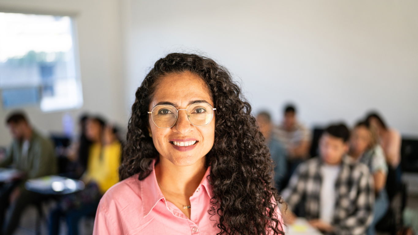 apl-prof.jpg Eine lächelnde außerplanmäßige Professorin in rosa Bluse und im Brille im Hörsaal