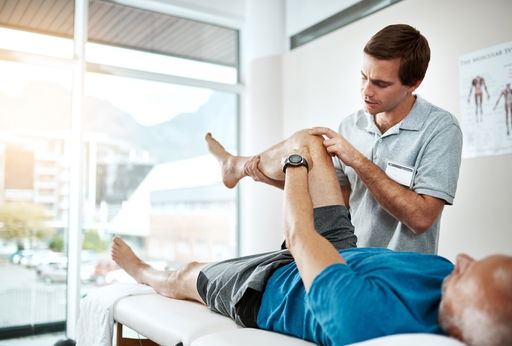 arbeiten-im-gesundheitswesen.jpg Arbeiten im Gesundheitswesen: Ein Physiotherapeut behandelt einen älteren Mann am Knie