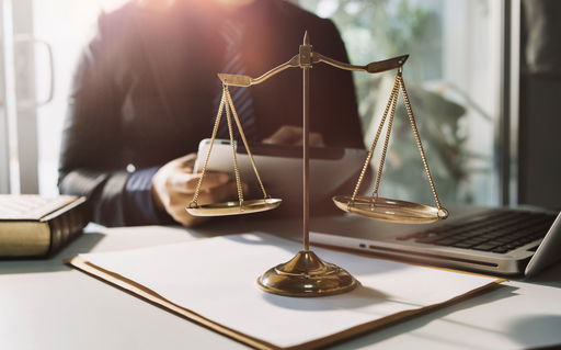 arbeitsrecht.jpg Eine Justitia-Waage auf dem Schreibtisch eines Mannes