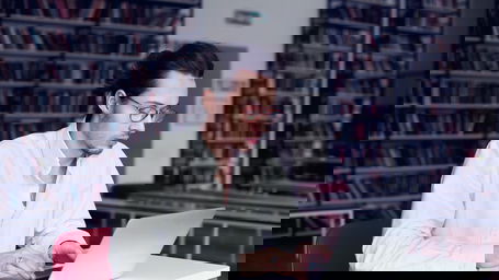 arten-der-promotion.jpg Ein Doktorand am Laptop in einer Bibliothek