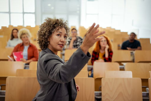 arten-von-professuren.jpg Eine Professorin im Hörsaal zeigt auf etwas