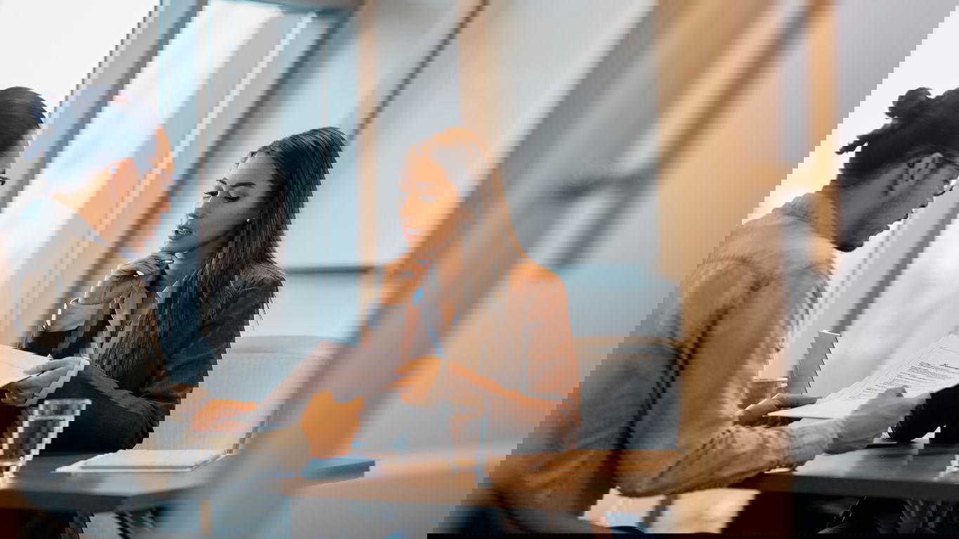 Bewerbung_Akademiker_iStock-1465697140.jpg Ein Personaler prüft bei einem Bewerbungsgespräch die Bewerbungsunterlagen der Bewerberin