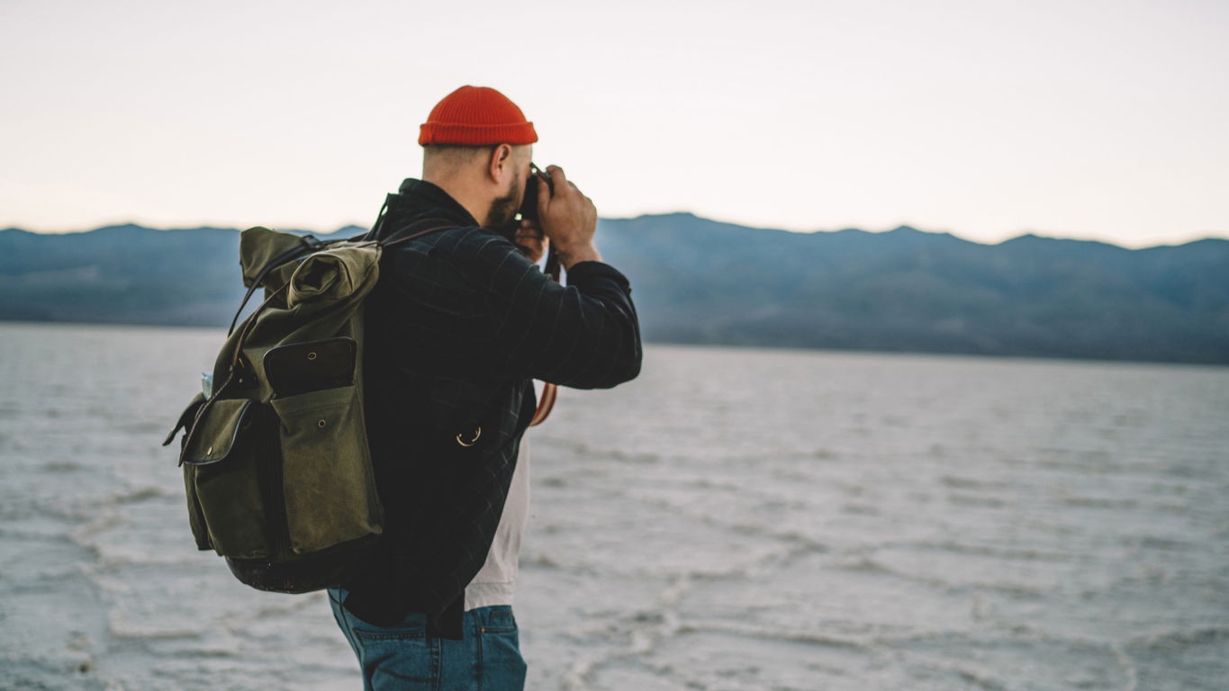 biologie-berufsaussichten.jpg Ein Biologe mit Rucksack macht Fotos an einem See