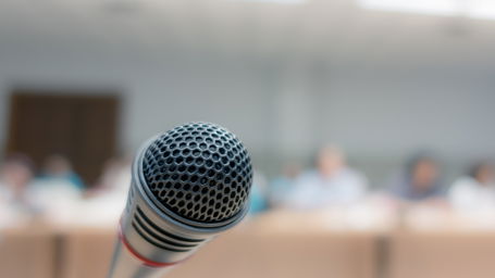 doktorarbeit-verteidigen.jpg Ein Mikrofon, im Hintergrund Professor:innen