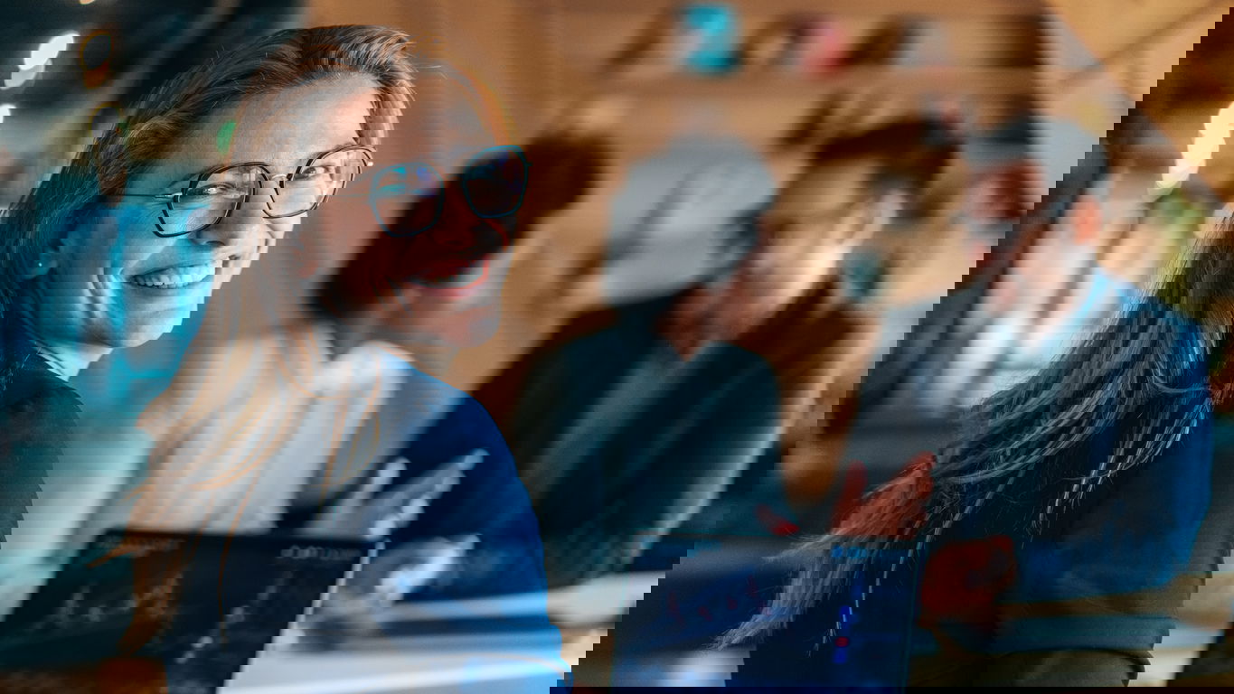 fürsorgepflicht_iStock-1442029571.jpg Eine glückliche Arbeitnehmerin am Laptop dank Fürsorgepflicht des Arbeitgebers