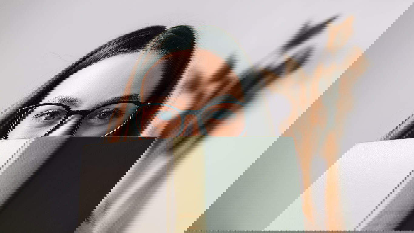 Germanistik-Frau-mit-Buch-iStock-1301623945.jpg Germanistik: Eine Frau mit Brille schaut hinter einem Buch hervor