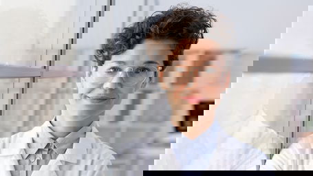 gruppenleiter-gehalt.jpg Eine Gruppenleiterin im weißen Laborkittel lehnt lächelnd an einer Scheibe