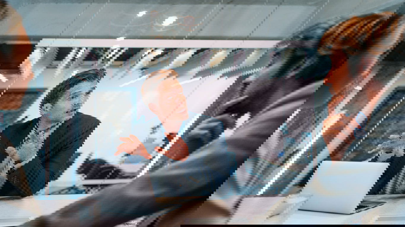 IT-Consultant_iStock-1362265062.jpg Ein IT-Consultant am Laptop erklärt zwei Menschen etwas