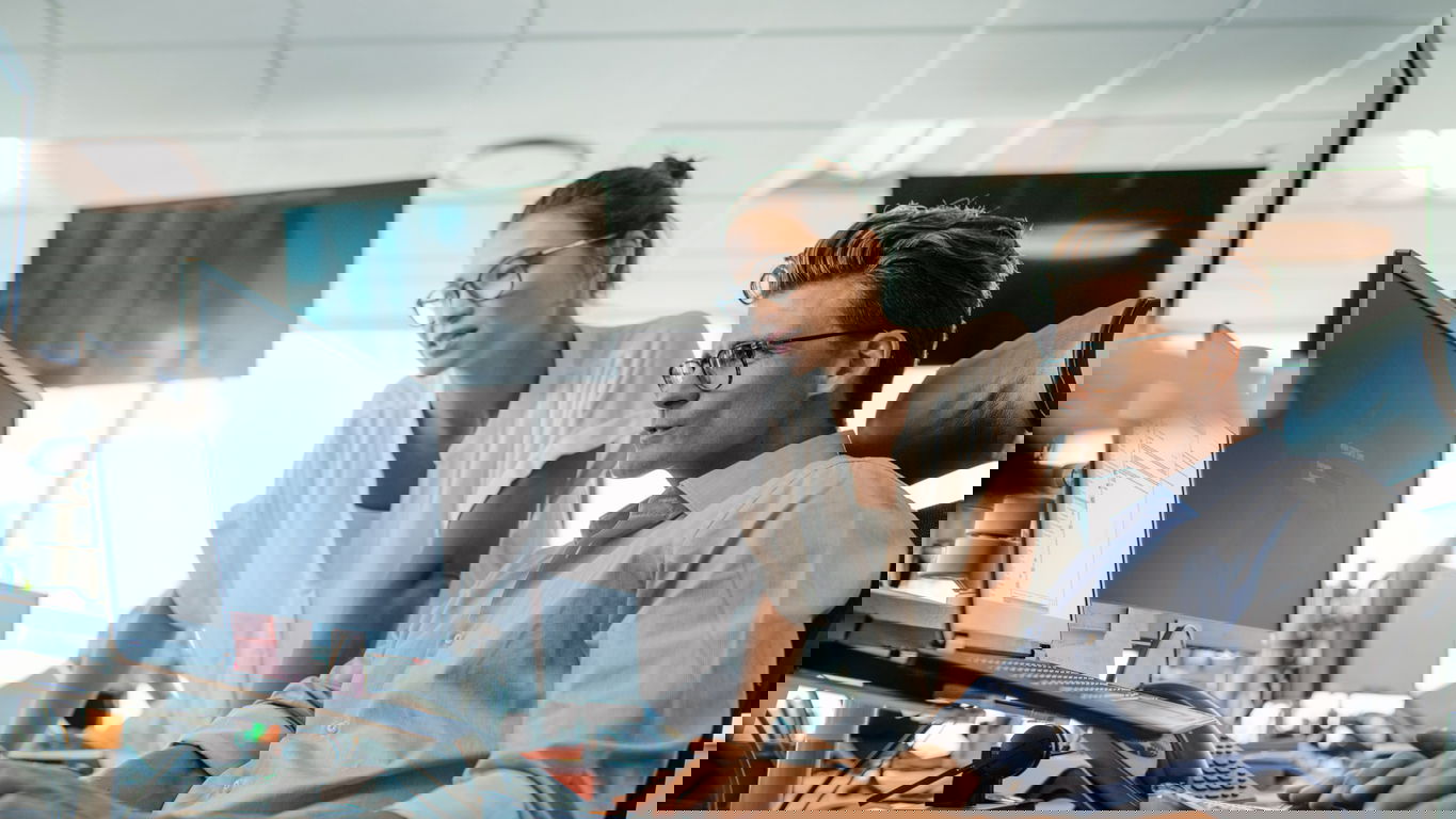 it-manager-berufsbild.jpg Ein IT-Manager mit einer Kollegin vor einem Monitor