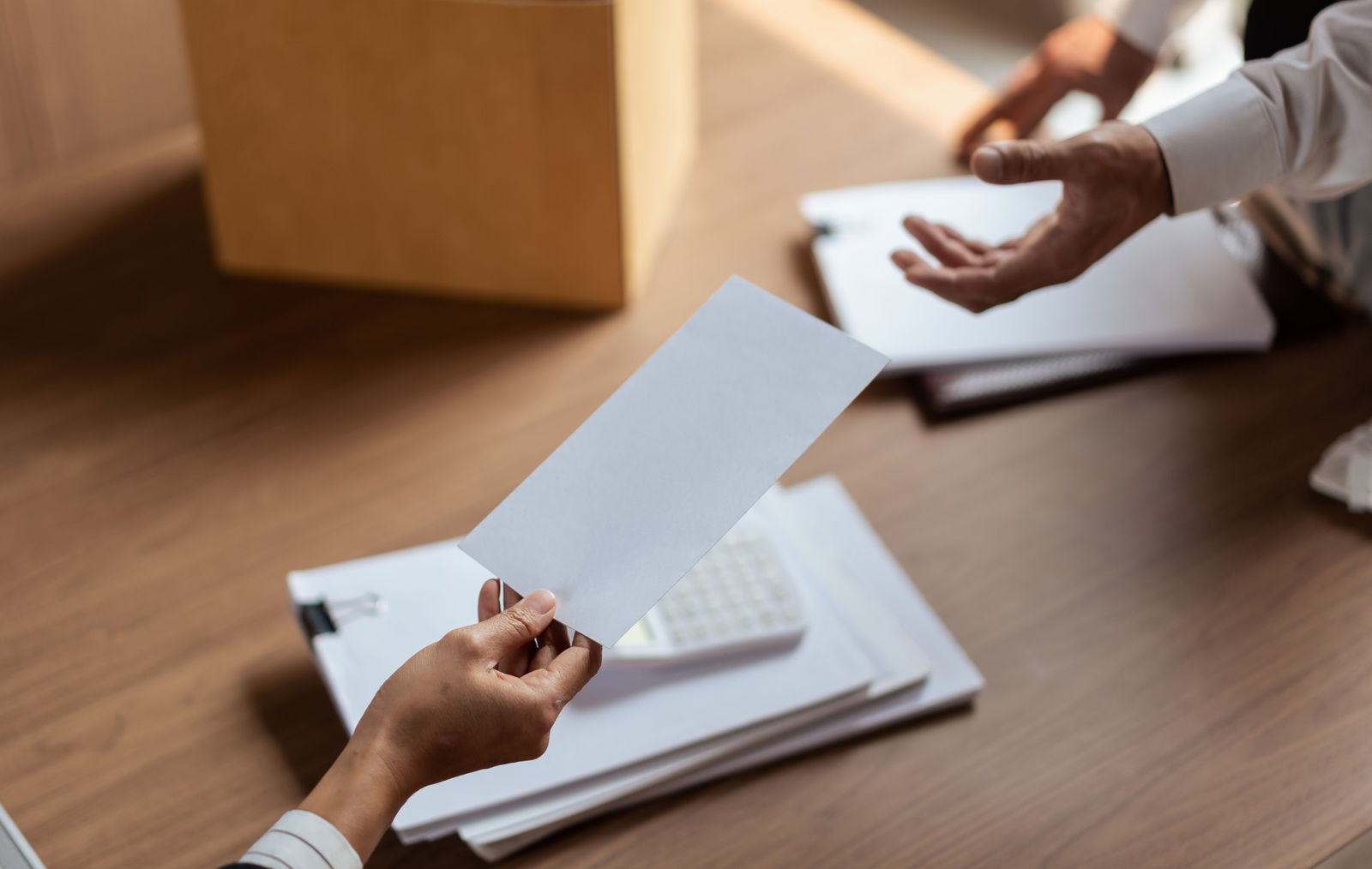 Eine Mitarbeiterin übergibt ihrem Chef ihr Kündigungsschreiben