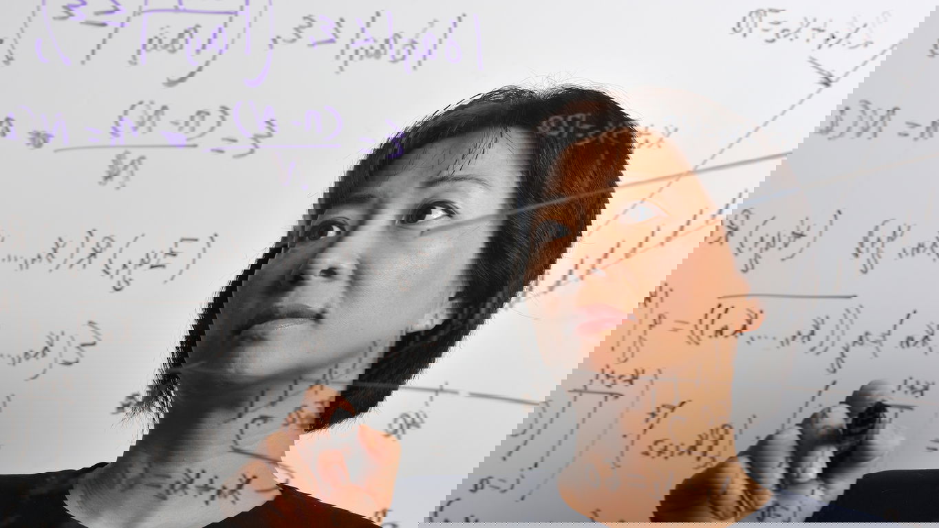 mathematiker-gehalt.jpg Eine asiatische Mathematikerin schreibt Formeln an eine Wand