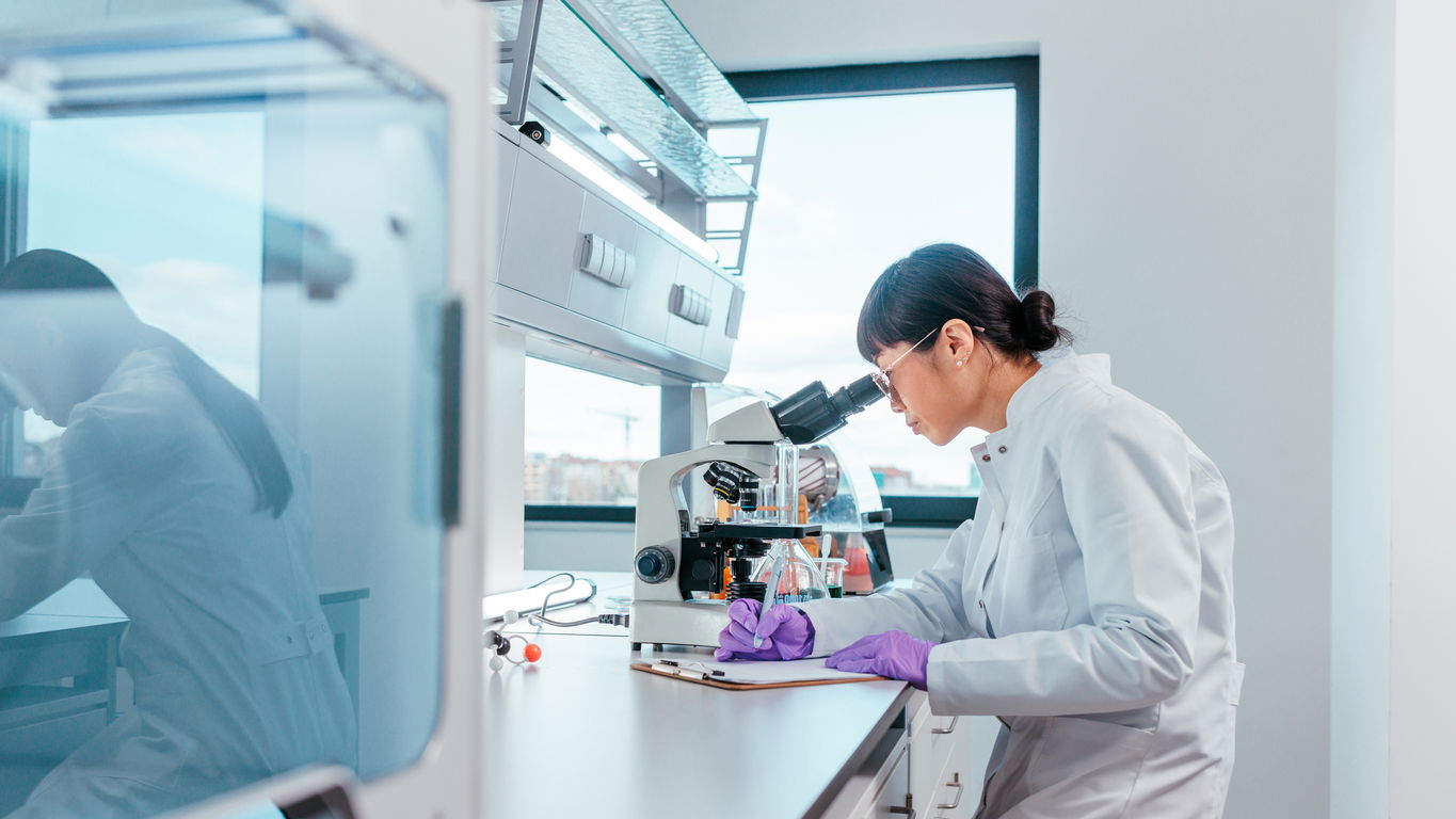 naturwissenschaften-gehalt.jpg Eine Naturwissenschaftlerin macht am Mikroskop Notizen