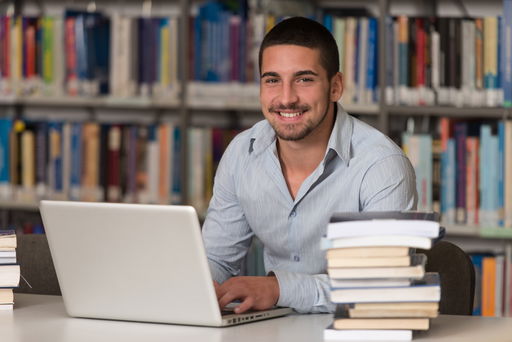 promotion.jpg Ein Doktorand in einer Bibliothek am Laptop