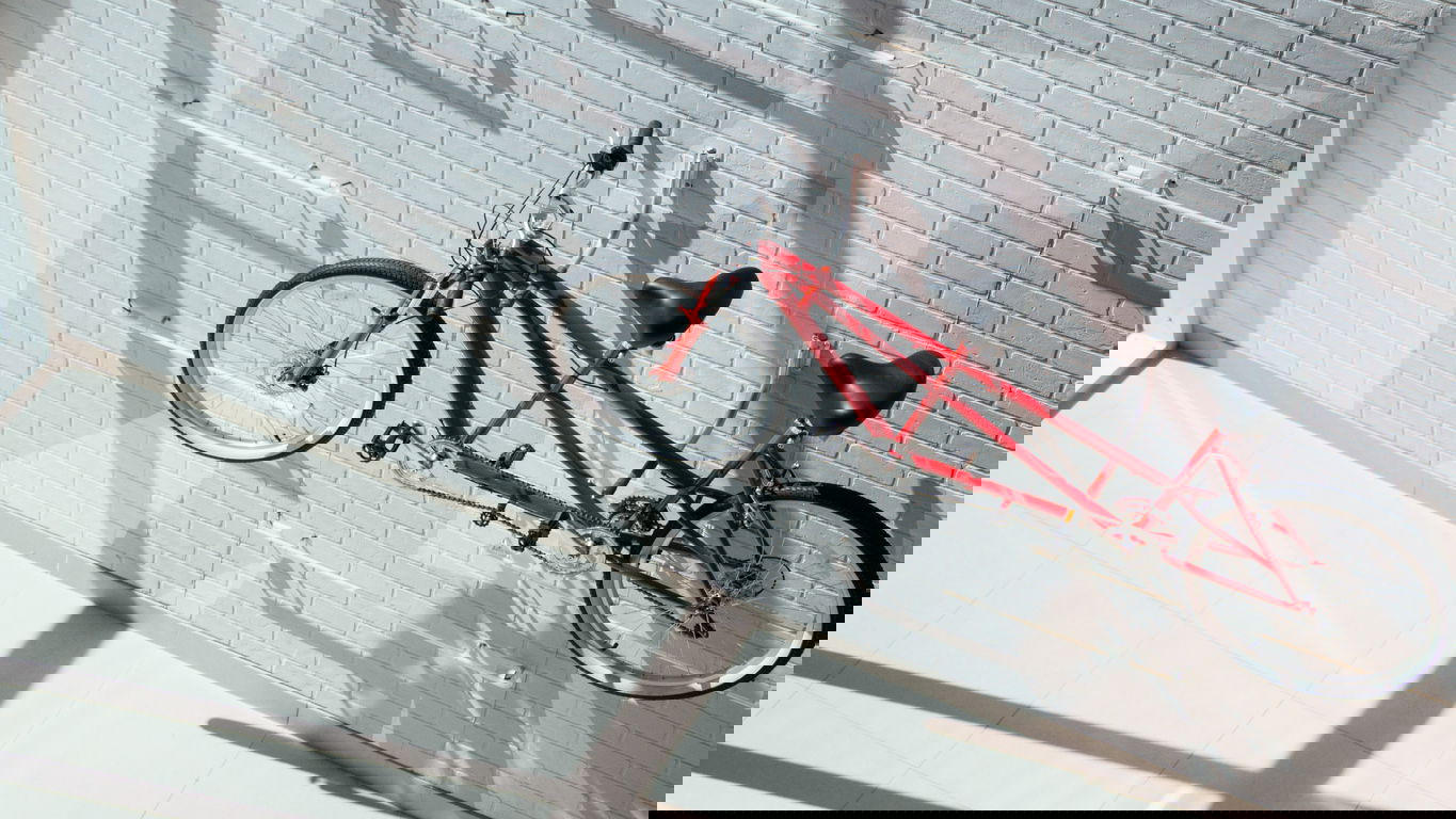 Tandemfahrred als Symbolbild Tandemprofessur adolfo-felix-Iqwlfc1cnnw-unsplash.jpg Ein rotes Tandemfahrrad hängt an einer Wand